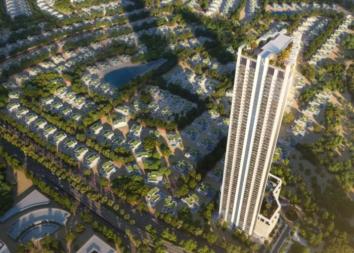 Aerial view of a luxury residential tower surrounded by green villas, landscaped community roads and water features in Dubai