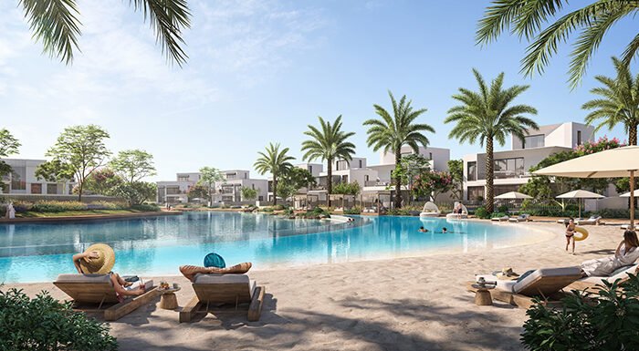 Luxury lagoon community with palm trees, waterfront villas, sandy beach seating and resort style swimming pool views