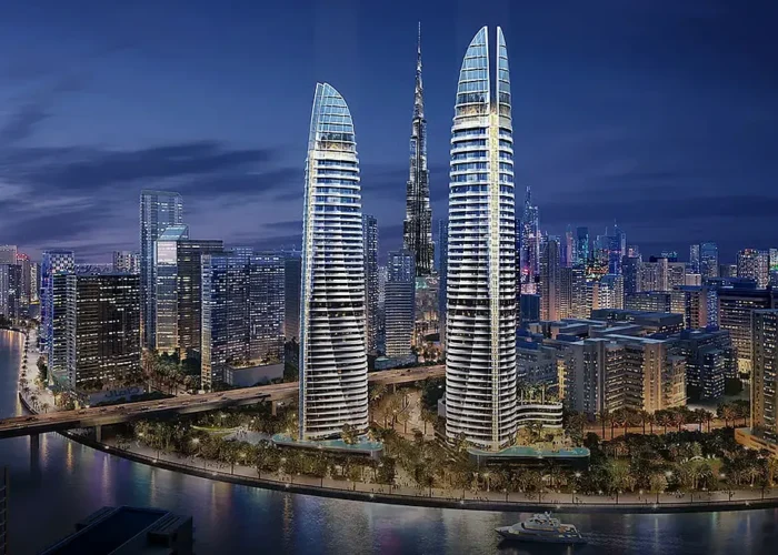 Twin luxury waterfront towers at night near Burj Khalifa with illuminated facades, river reflections and Dubai skyline views