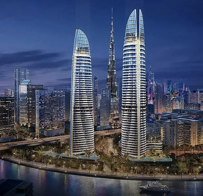 Twin luxury waterfront towers at night near Burj Khalifa with illuminated facades, river reflections and Dubai skyline views