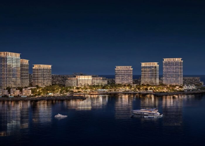 Luxury waterfront island residences at night with illuminated towers, calm sea reflections, yachts and premium coastal living views