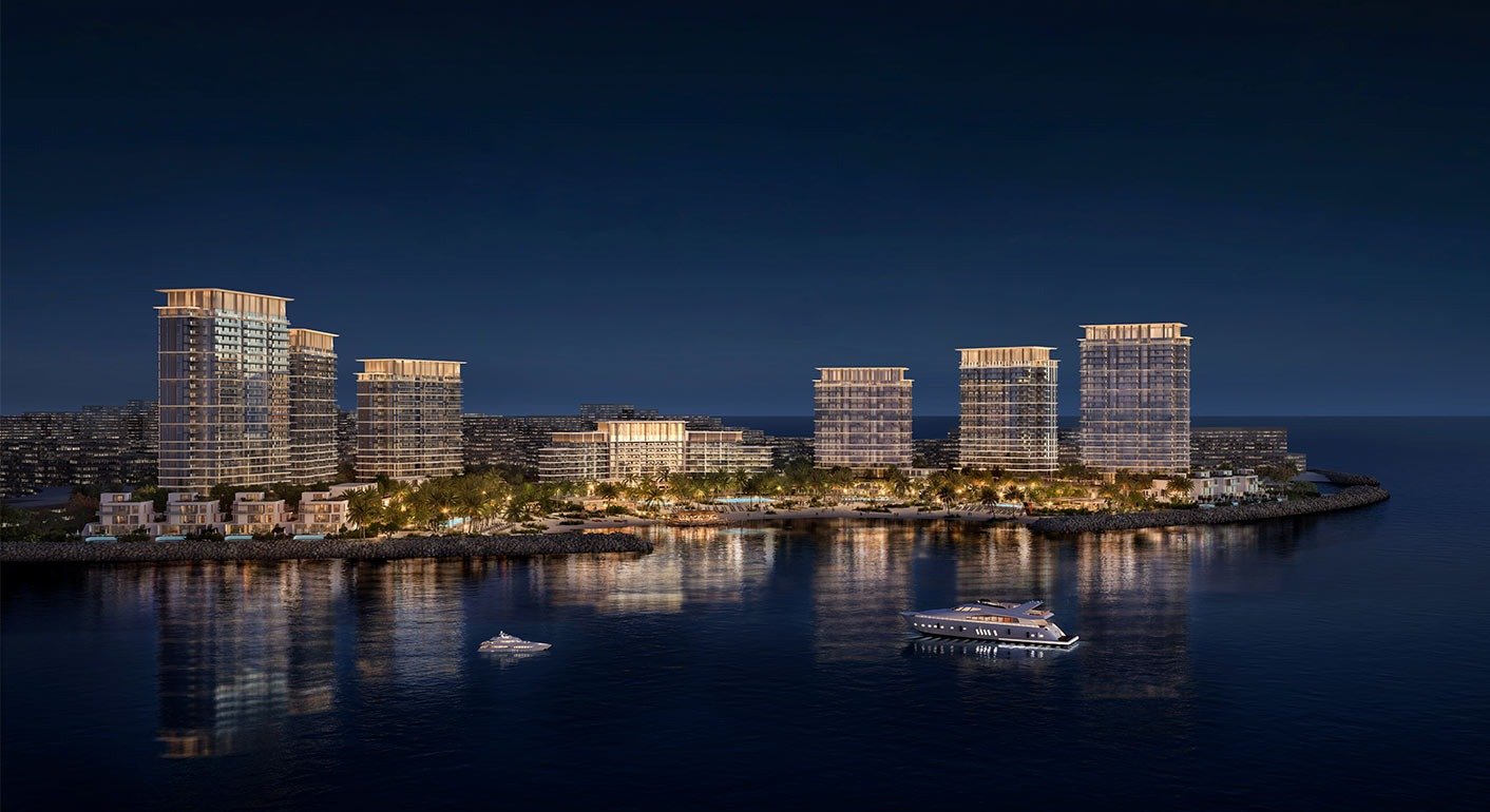 Luxury waterfront island residences at night with illuminated towers, calm sea reflections, yachts and premium coastal living views
