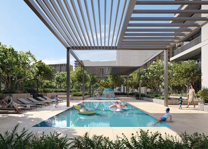 Family swimming pool in modern residential community with shaded pergola, kids play area, loungers and lush greenery