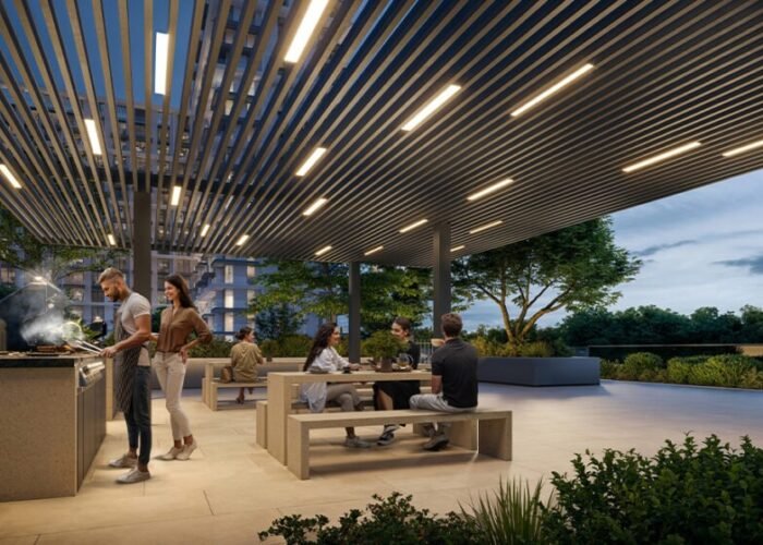 Residents enjoying outdoor BBQ lounge with modern seating, pergola lighting, landscaped greenery and community living space