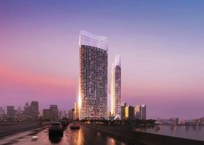 Luxury waterfront towers at sunset with illuminated facades, road access, river reflections and modern city skyline views